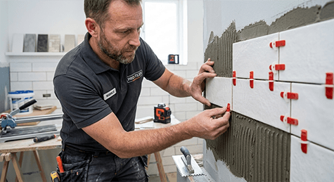 Fliesenleger verlegt Wandfliesen mit Fliesenkleber in einem Badezimmer